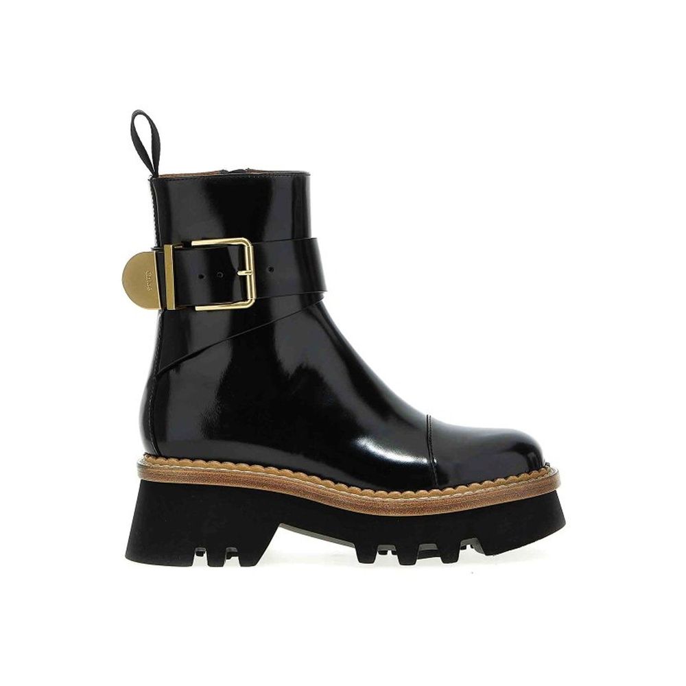 Black glossy boot with gold buckle on a white background